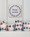 Boerenbont ceramic tile featuring "Old cups, new stories" and traditional Dutch floral motifs, displayed above a collection of matching Boerenbont cups.