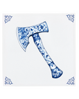 An axe on a Delft Blue ceramic tile with decorative corner ornaments