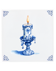 A lit candle on a Delft Blue ceramic tile with decorative corner ornaments