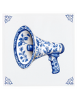 A megaphone on a Delft Blue ceramic tile with decorative corner ornaments
