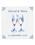 Two champagne glasses toasting on a Delft Blue ceramic tile with decorative corner ornaments