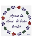 A square white ceramic tile featuring the French phrase 'Apres la pluie, le beau temps' in dark purple script, surrounded by a decorative Boerenbont border. [market:fr]
