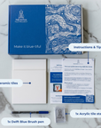 DIY kit contents displayed on a marble surface, including two ceramic tiles, a bent brush, an acrylic stand and instruction cards. [market:!nl]