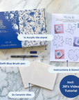 DIY kit contents displayed on a marble surface, including two ceramic tiles, a bent brush, an acrylic stand and instruction cards. [market:!nl]