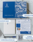 DIY kit contents displayed on a marble surface, including two ceramic tiles, a bent brush, an acrylic stand and instruction cards. [market:nl]
