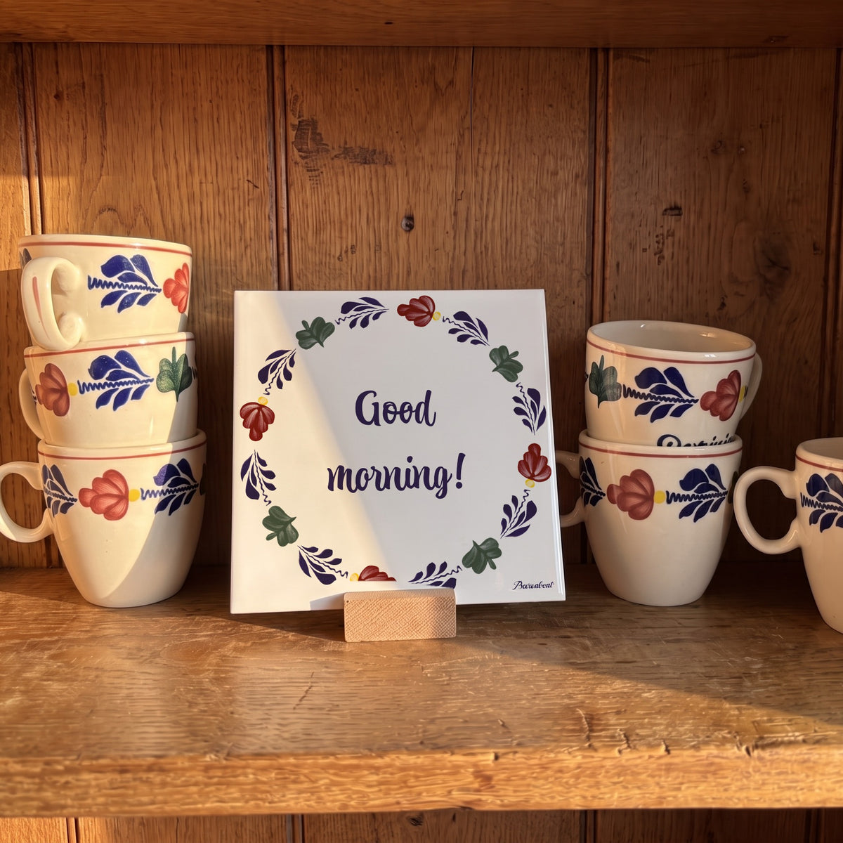 Boerenbont ceramic tile featuring the greeting "Good morning!" with colourful Dutch floral patterns, displayed alongside matching Boerenbont coffee mugs. [market:!nl,!de,!at,!fr]