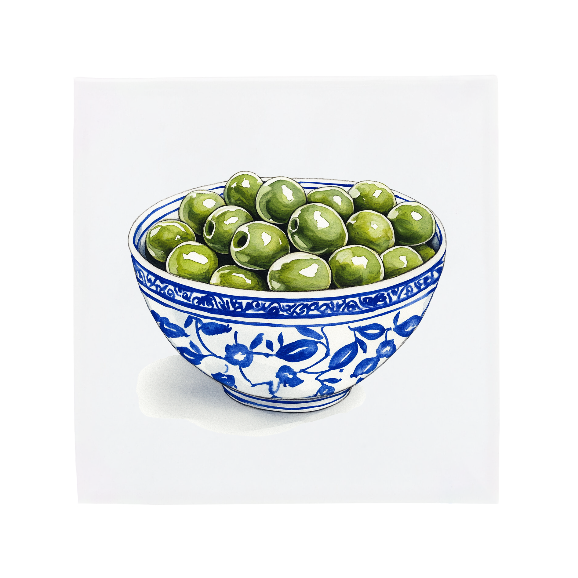Ceramic bowl with blue floral patterns filled with green olives on a Delft Blue tile on a white background