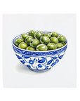Ceramic bowl with blue floral patterns filled with green olives on a Delft Blue tile on a white background
