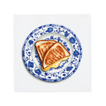 Two pieces of grilled cheese sandwich on a decorative blue and white plate with floral patterns on a tile.