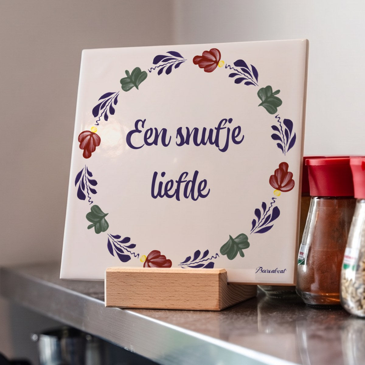 Decorative Boerenbont ceramic tile featuring the Dutch saying "Een snufje liefde" with colourful floral patterns, displayed alongside kitchen spices.