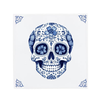 Delfts Blauwe keramische tegel met een Dia de los Muertos-schedel en de herkenbare The Dutch Tile hoekornamenten, een moderne twist op de klassieke Hollandse tegel.